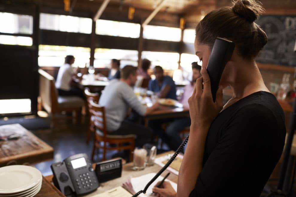 Restaurant staff member handling a reservation phone call