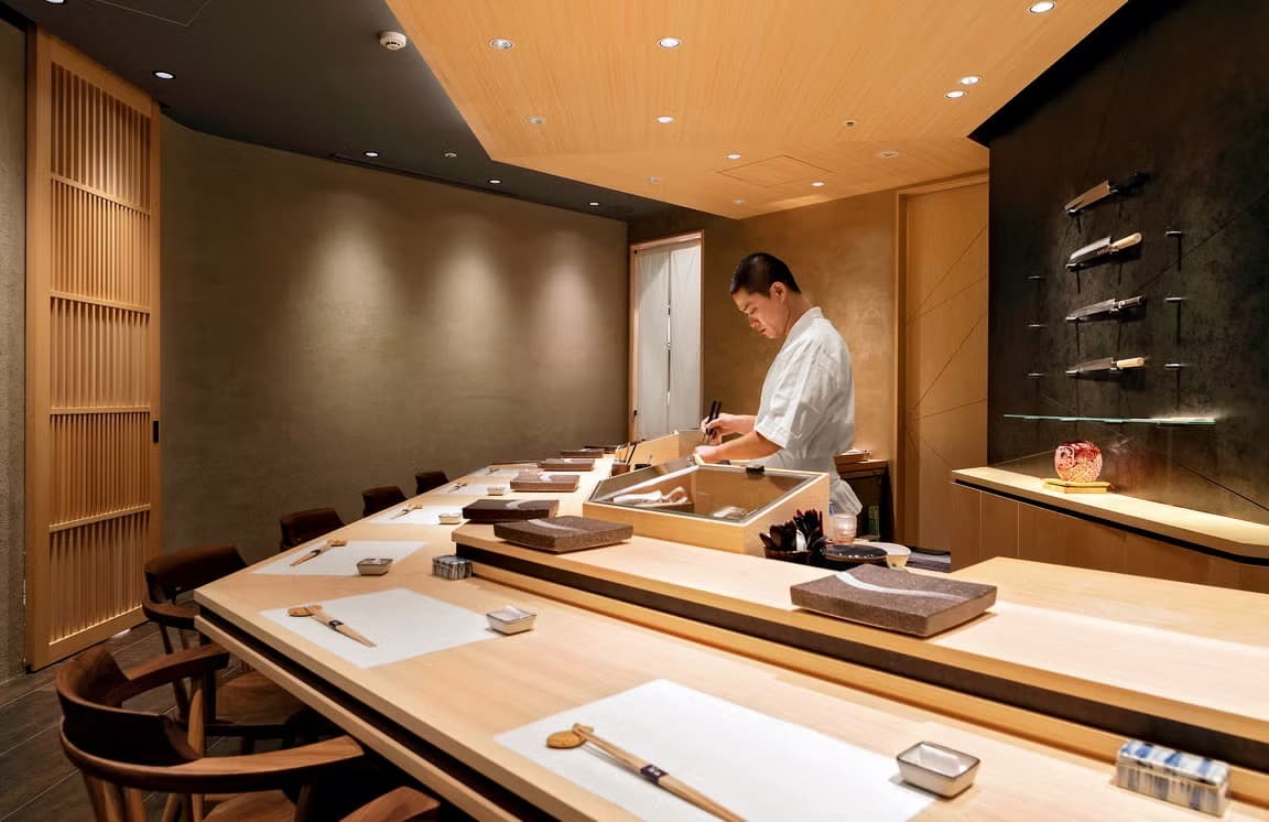 Sushi chef preparing food behind a Japanese sushi counter