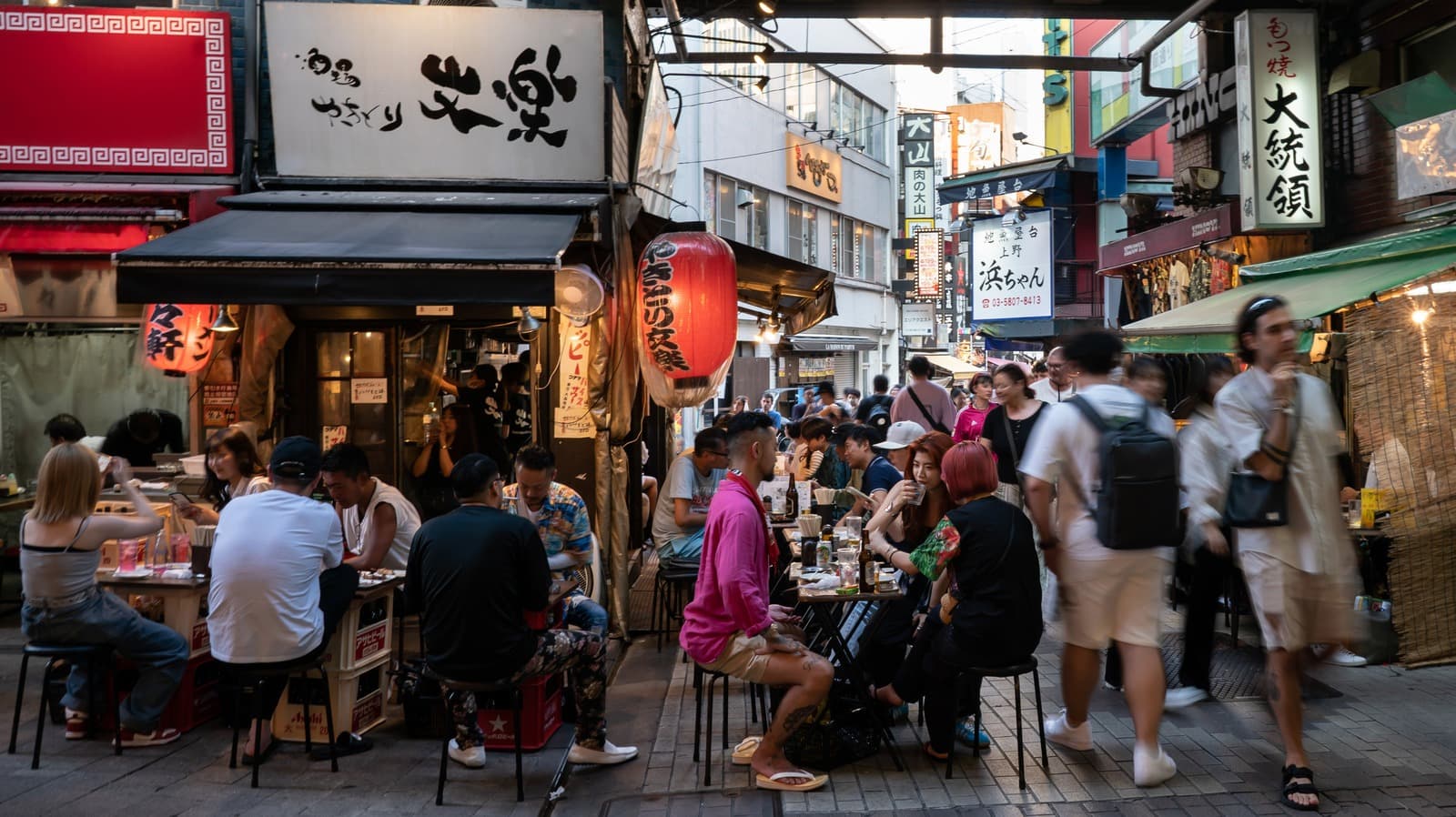 Travelers dining and walking through a busy Tokyo restaurant street