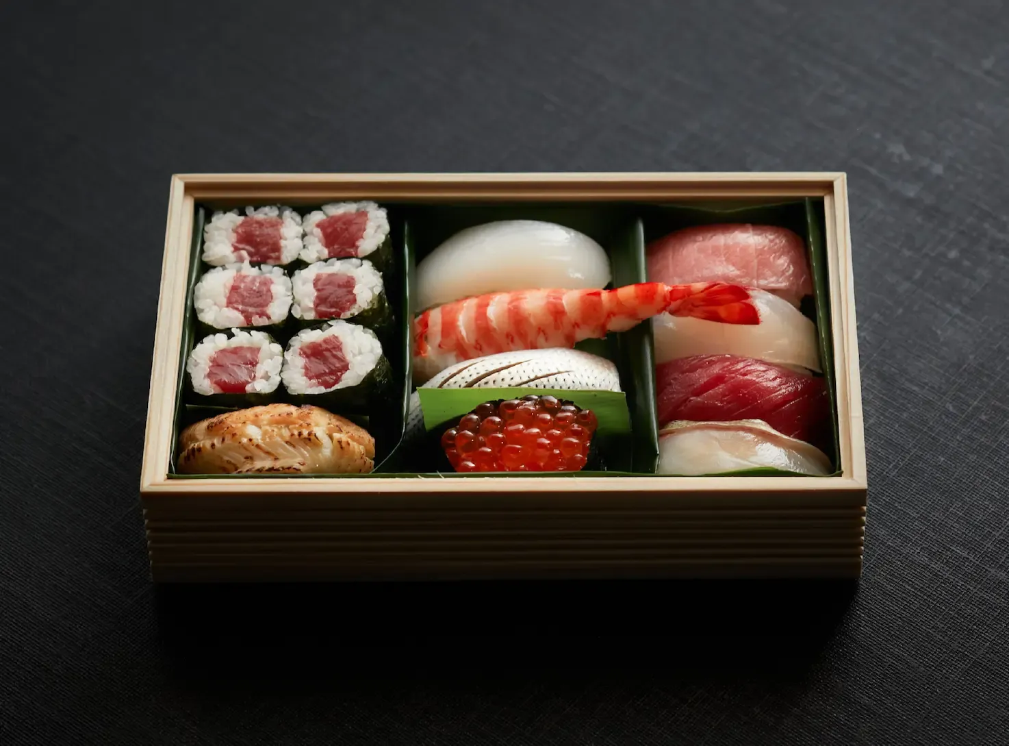 Assorted sushi pieces arranged in a wooden box
